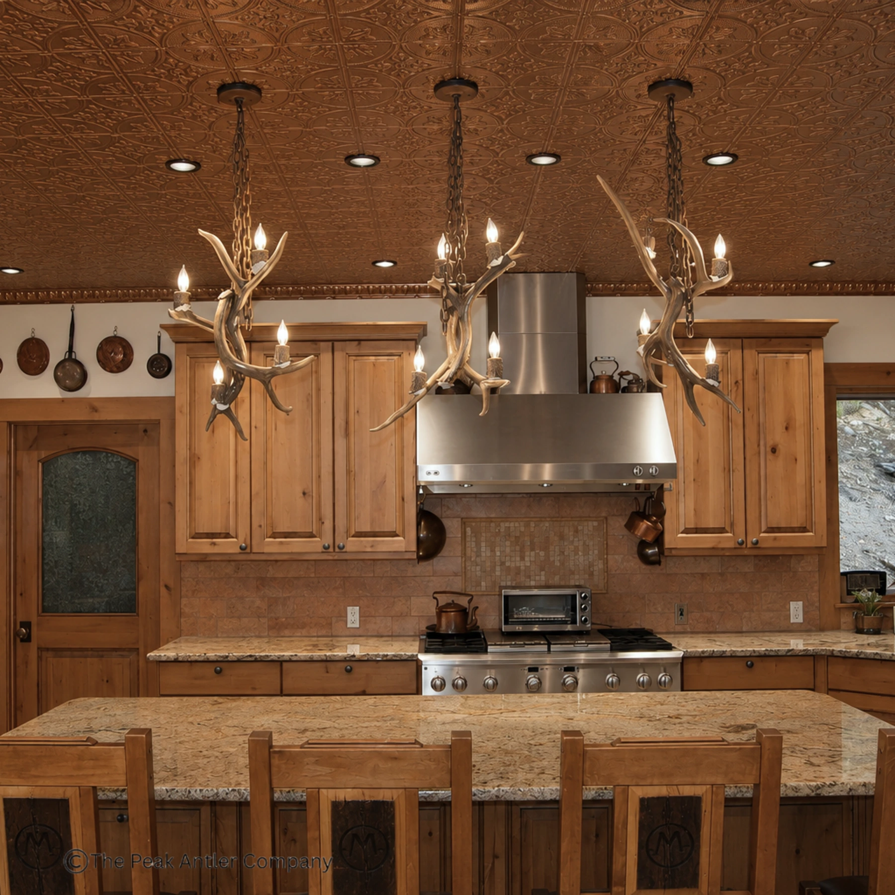 three mule deer antler pendant lights over a home kitchen island
