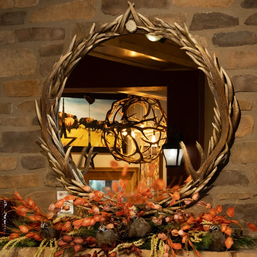 A large antler mirror reflecting a unique globe antler chandelier