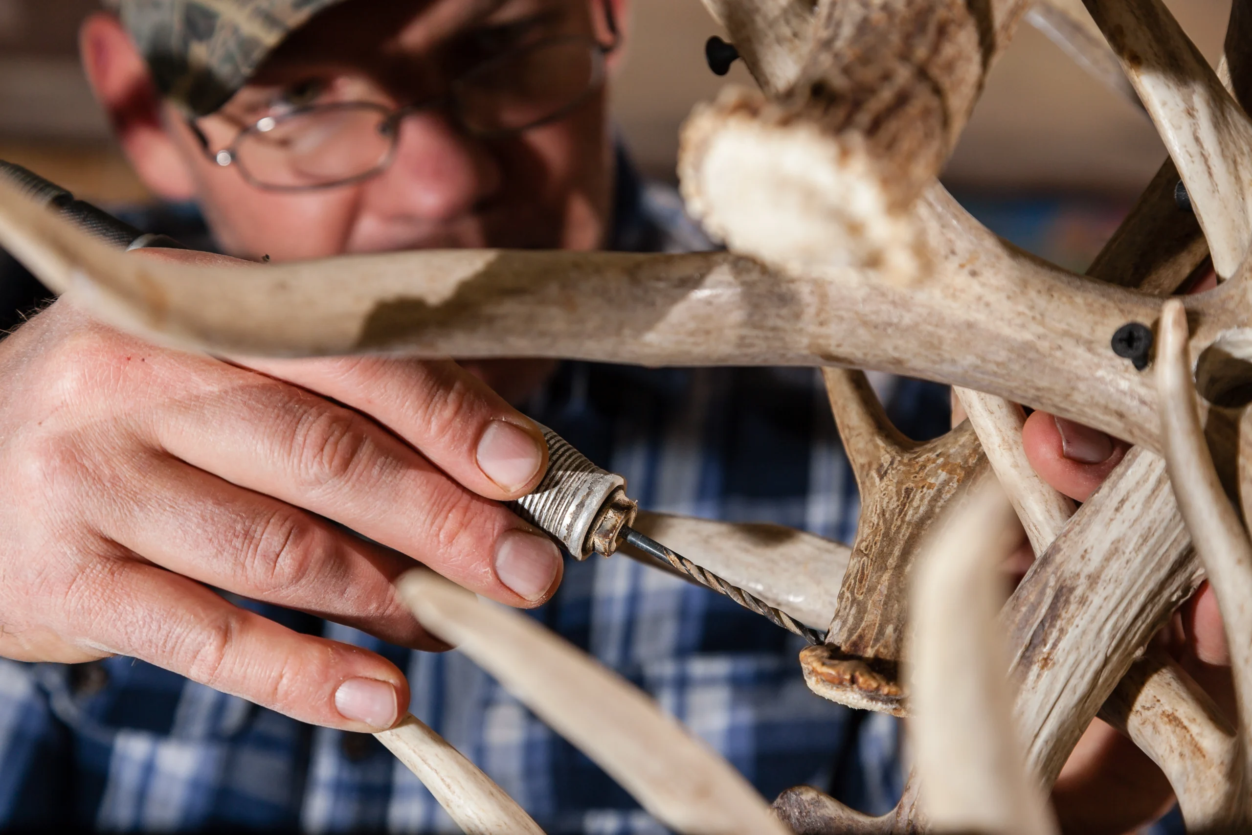 Close up of Jeff Musgrave drilling screws into an antler chandelier