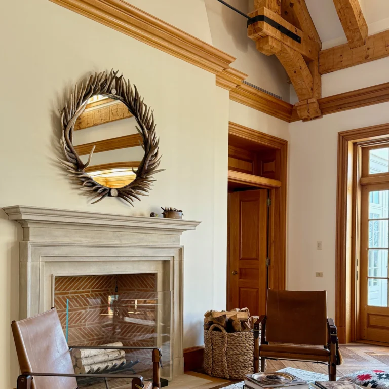 Elk antler framed round mirror hanging above fireplace