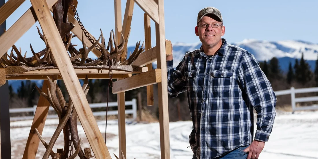 Jeff Musgrave posing next to a two tier antler chandelier
